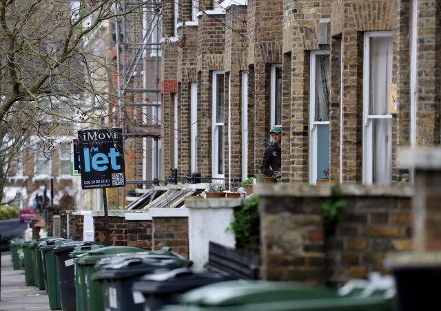 A man looks out from a house on a residential street in South London, Britain, February 26, 2024. REUTERS/Hannah McKay