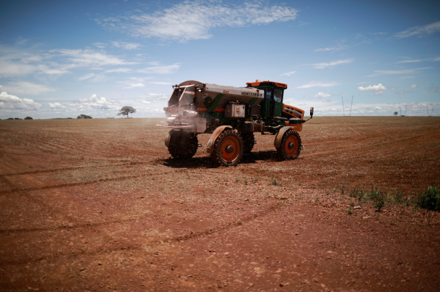 An agricultural worker drives a tractor spreading fertilizer in a soybean field, near Brasilia, Brazil February 15, 2022. REUTERS/Adriano Machado