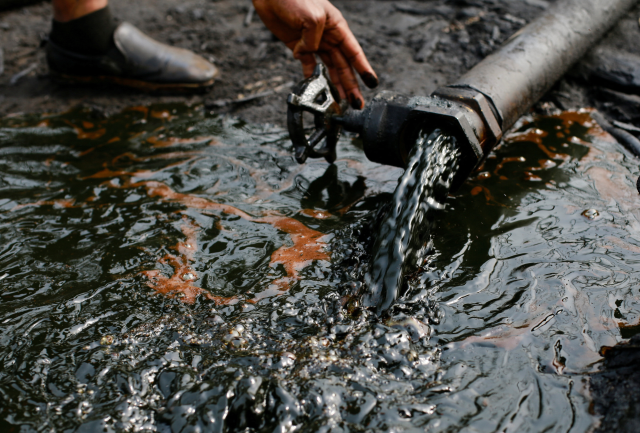 A person operates a tap of crude oil during the destruction of Bakana ii illegal camp, in Okrika, Rivers state, Nigeria January 28, 2022. REUTERS/Afolabi Sotunde