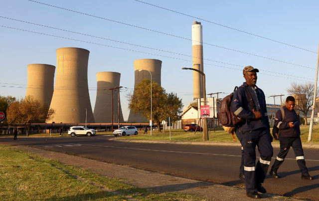 Workers walk past a coal-fired Komati Power Station, operated by Eskom near Komati village, in the Mpumalanga province in South Africa, May 9, 2024. REUTERS/Siphiwe Sibeko