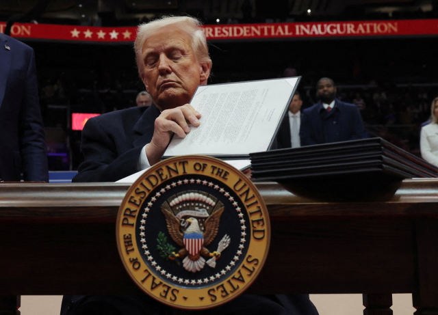 U.S. President Donald Trump signs an executive order during the inaugural parade inside Capital One Arena on the inauguration day of his second presidential term, in Washington, U.S. January 20, 2025. REUTERS/Carlos Barria