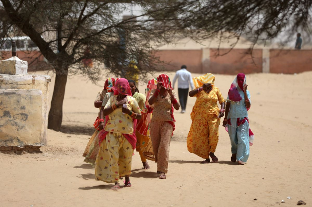 Women cover their faces to protect from heat as they arrive at a polling station to cast their votes during the first phase of the general election, in Bikaner district, Rajasthan, India, April 19, 2024. REUTERS/Amit Dave