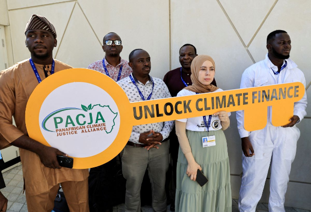 Activists hold a sign that reads "Unlock Climate Finance" at the United Nations Climate Change Conference COP28 in Dubai, United Arab Emirates, December 5, 2023. REUTERS/Thaier Al-Sudani