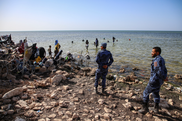 Libyan security personnel stand by the migrants from Africa next to the seashore at the Libyan-Tunisian border in Ras Ajdir, Libya July 23, 2023. REUTERS/Hazem Ahmed