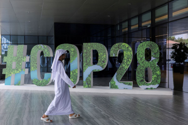 A person walks past a "#COP28" sign during The Changemaker Majlis, a one-day CEO-level thought leadership workshop focused on climate action, in Abu Dhabi, United Arab Emirates, October 1, 2023