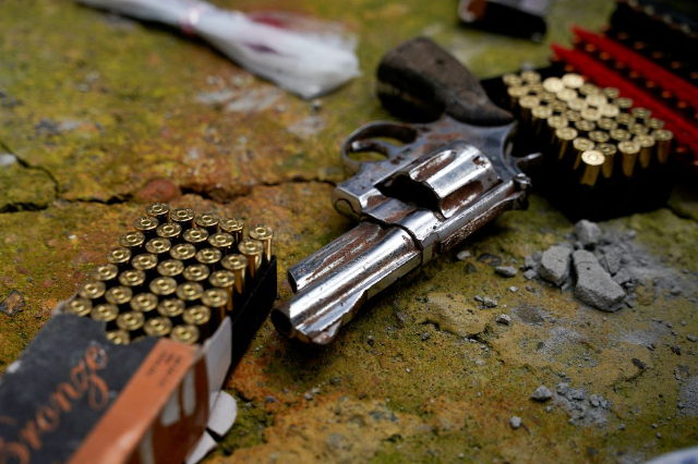 A revolver and bullets lay on the ground after they were found during a joint police and military operation in a low-income neighbourhood, as the government continues its offensive against criminal gangs, in Duran, Ecuador, February 1, 2024. REUTERS/Santiago Armas