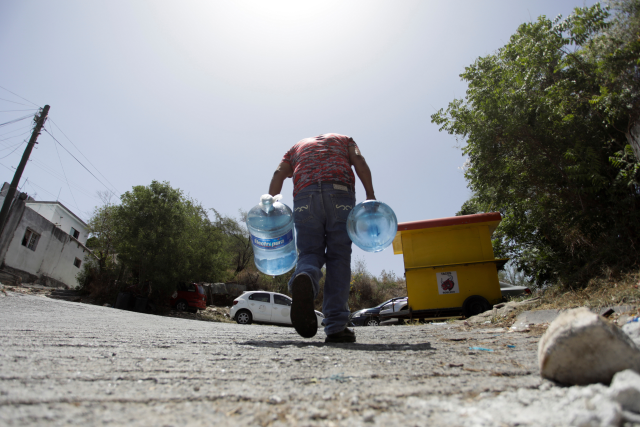 A man walks with bottles to collect water from the public water supply as more than half of Mexico faces moderate to severe drought conditions, in Monterrey, Mexico June 16, 2022. REUTERS/Daniel Becerril