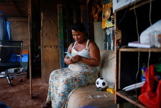 A woman uses a cell phone in her home near Planalto Palace, in Brasilia, Brazil March 3, 2021