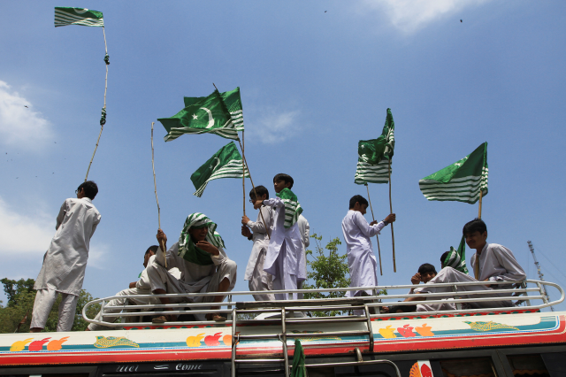Supporters of the Pakistan Markazi Muslim League (PMML), carry flags as they stand on top of a van during a protest against the suspension of Indus Waters Treaty by India, in Lahore, Pakistan April 24, 2025. REUTERS/Mohsin Raza