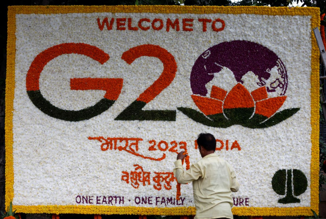 A man decorate a hoarding with flowers on a pavement ahead of the G20 Summit in New Delhi, India, September 8, 2023