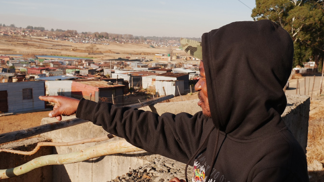Zethu Hlatshwayo, Khuthala's spokesperson, points to Nomzamo from a viewpoint, Ermelo, South Africa, July 9, 2025. Thomson Reuters Foundation/Kim Harrisberg