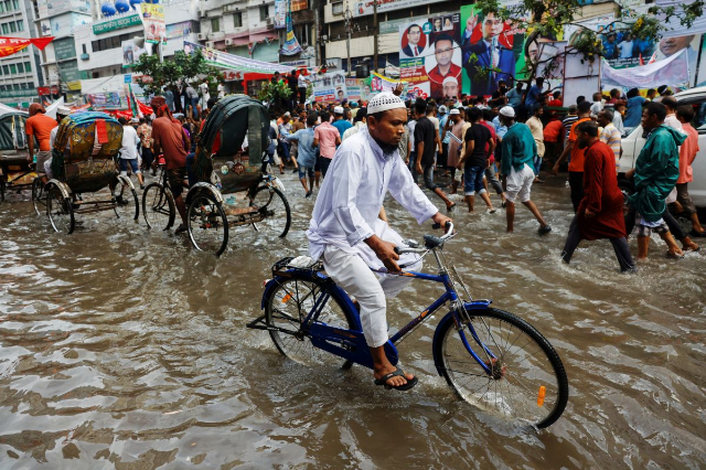 A man rides a bicycle on a flooded streets after rain in Dhaka, Bangladesh, August 4, 2023