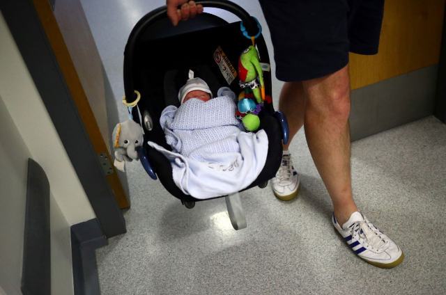 A nine week old baby is carried in a car seat by his father as they leave hospital after being discharged from the Lancashire Women and Newborn Centre of Burnley General Hospital in East Lancashire in Burnley, Britain, June 22, 2020. REUTERS/Hannah McKay