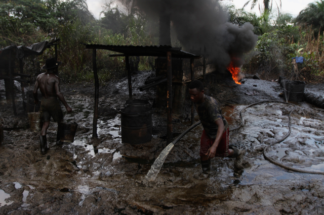 Men work at an illegal oil refinery site near river Nun in Nigeria's oil state of Bayelsa November 27, 2012. REUTERS/Akintunde Akinleye