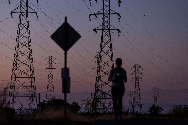 A woman jogs by power lines in Mountain View, California, U.S., August 17, 2022. REUTERS/Carlos Barria