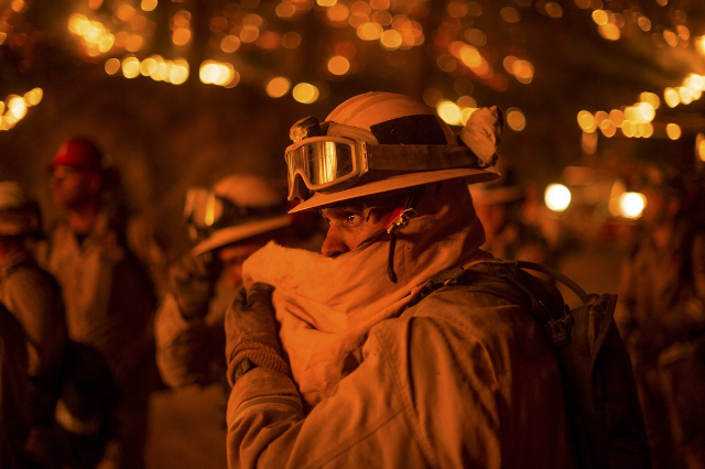 A firefighter covers his face while battling the Butte fire near San Andreas, California September 12, 2015.