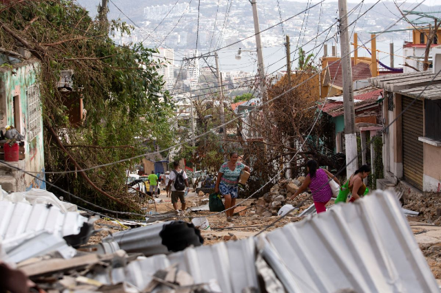 People walk among rubble in the aftermath of Hurricane Otis, in Acapulco, Mexico, October 27, 2023. REUTERS/Quetzalli Nicte-Ha