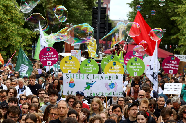 People hold a sign that reads "Be a climate hero and save the world!", as Fridays for Future demonstrate for a social and climate-friendly Europe near the Brandenburg Gate in Berlin, Germany, May 31, 2024. REUTERS/Christian Mang